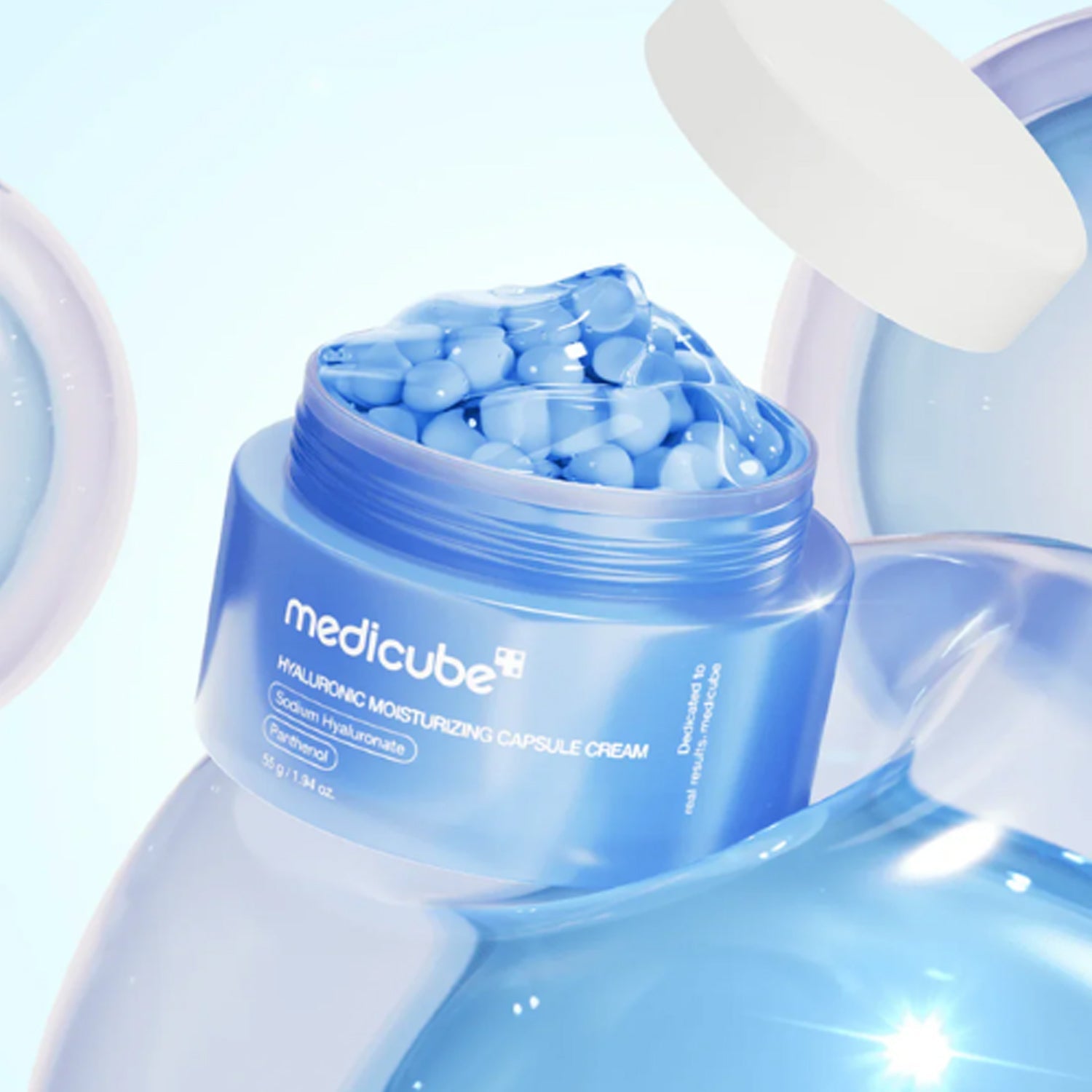 Crystal-clear gel texture with floating white moisturizing capsules of Medicube Hyaluronic Capsule Cream melting into skin at Atelier De Glow UAE.