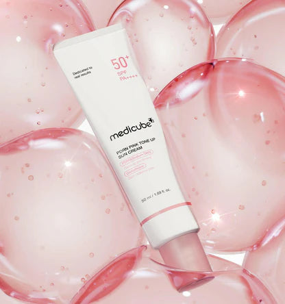 Air-light, ultra-adherent, and peach-tinted cream texture of Medicube PDRN Pink Tone Up Sun Cream gliding smoothly over a clear profile at Atelier De Glow UAE.